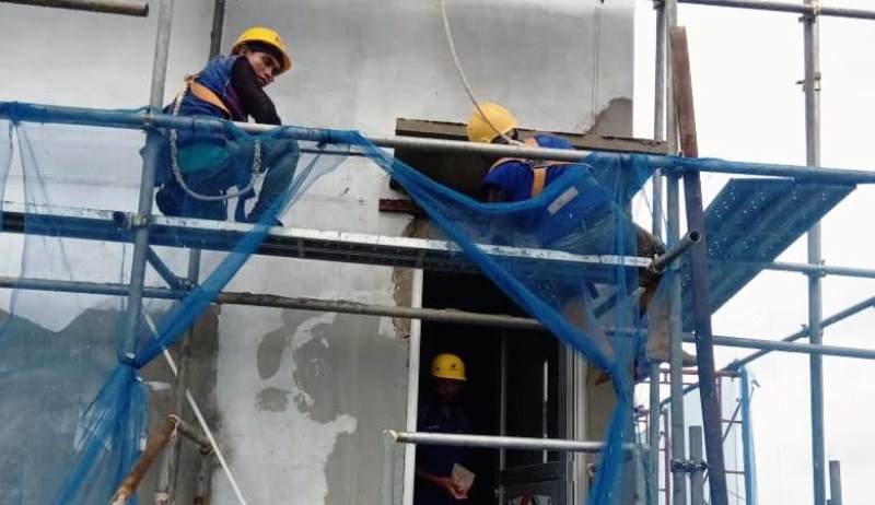 Pekerja konstruksi melaksanakan pekerjaan pada perancah